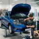 Mecánico profesional realizando un cambio de aceite y filtros en un Renault Megane azul dentro de un taller mecánico limpio